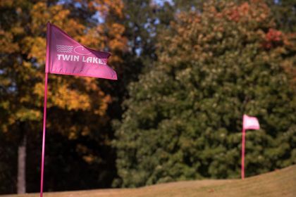 2 pink flags with Twin Lakes logo with trees in background